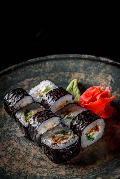 istock sushi roll with eel, cucumber, cream cheese, rice in plate on black wooden table background 1217023041