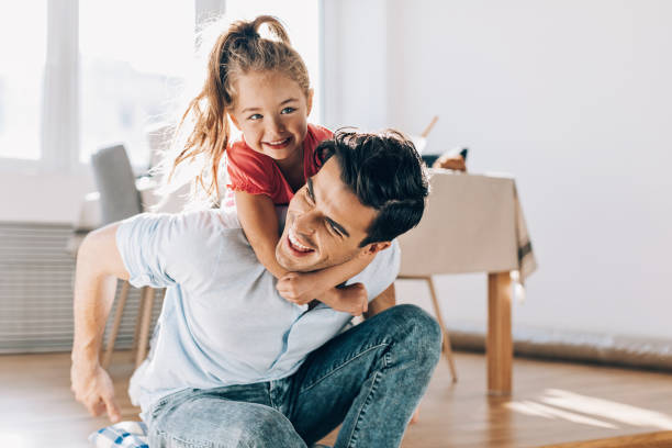 padre che gioca con la sua bambina a casa - child candid indoors lifestyles foto e immagini stock