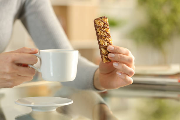 istock Girl hands holding snack bar and coffee cup at breakfast 1217023313