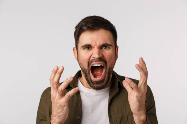 istock Man losing temper feeling aggression and depression. Distressed and bothered bearded male fed up, tired of arguing shouting, shaking hands aggressive and cursing someone, look angry, white background 1217023666