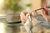 Woman hands cleaning glasses with tissue at home