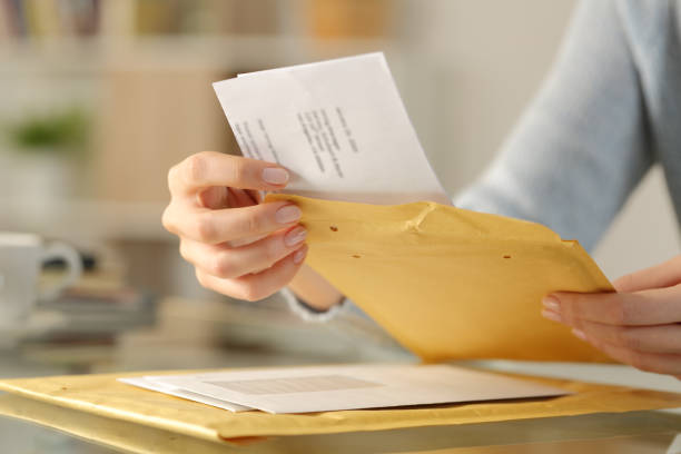 mãos de mulher abrindo um envelope acolchoado em uma mesa - opening mail envelope greeting card - fotografias e filmes do acervo