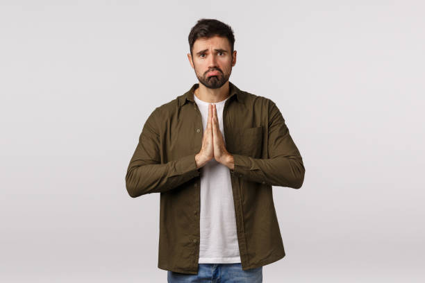 istock Upset, miserable and gloomy cute bearded guy in casual outfit, begging for help need something, press palms together asking offer, praying, supplicating, ask apology, white background 1217024921