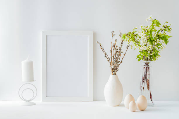 istock Home interior with easter decor. Mockup with a white frame and spring flowers in a vases on a light background 1217025149