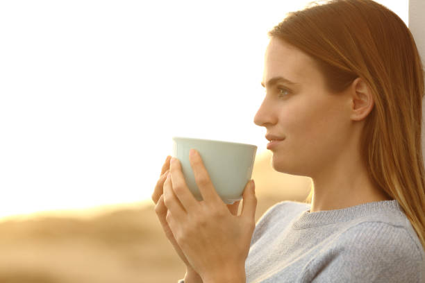 istock Pensive woman relaxing drinking coffee at sunset 1217026201