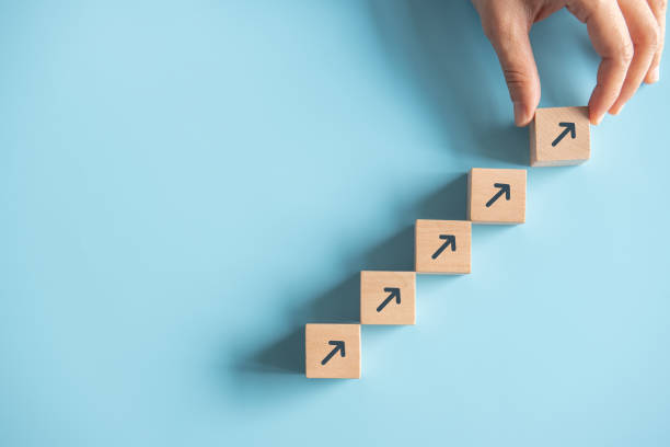 istock Close up man hand arranging wood block stacking as step stair on paper pink background. Business concept growth success process, copy space. 1217026295