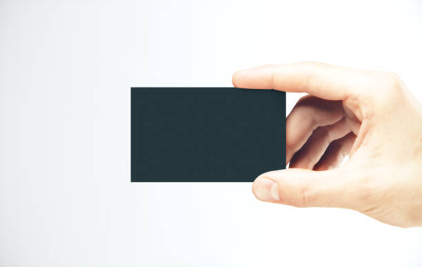 istock Hand holding a blank black business card. 1217026486