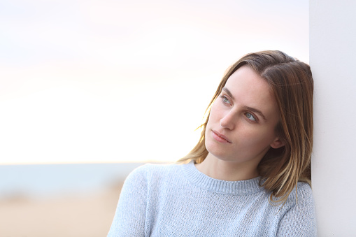 Portrait of a pensive serious woman looking away on the beach with copy space
