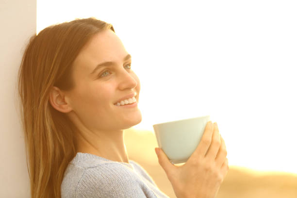 istock Happy woman dreaming drinking coffee at sunset 1217026628