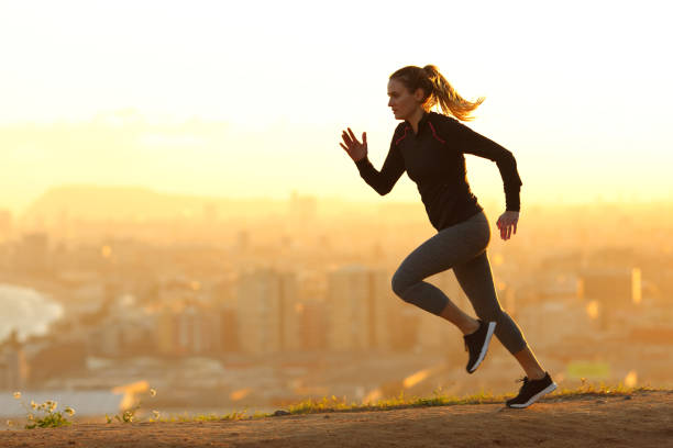 Runner woman running in the outskirts of the city Side view full body portrait of a runner woman running in the outskirts of the city at sunset sports race photos stock pictures, royalty-free photos & images
