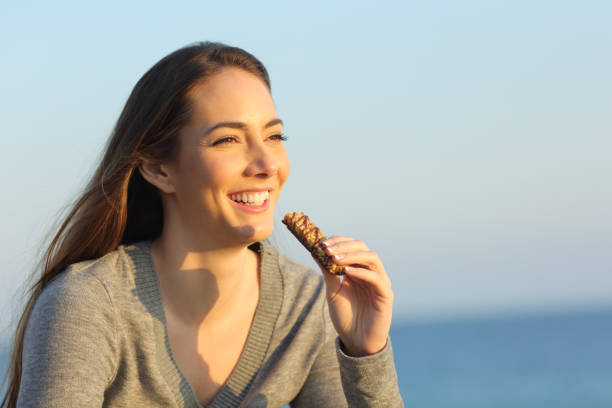 istock Happy woman eating snack on the beach 1217028241