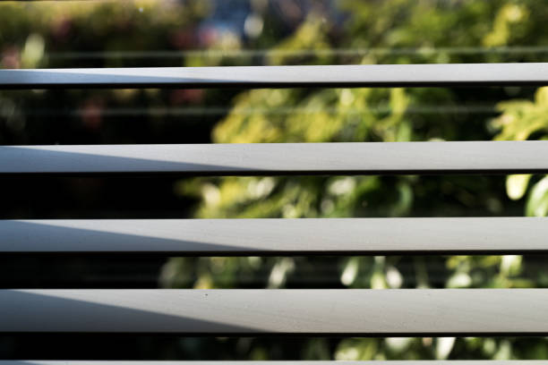 Viewpoint from interior of house through venetian blinds towards front yard and street beyond.  Selective focus.  Belfast, Northern Ireland.
