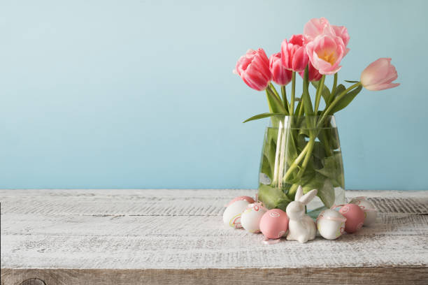 istock Wicker basket with easter eggs and pink tulips. Spring easter blue background with space for text. 1217028923