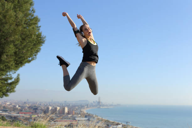 Excited runner wearing headphones jumping celebrating success