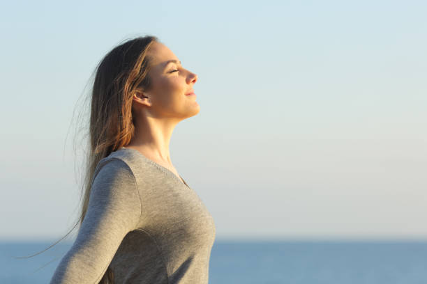 Woman breaths fresh air on the beach Side view portrait of a relaxed woman breathing fresh air on the beach women healthy lifestyle beauty nature stock pictures, royalty-free photos & images