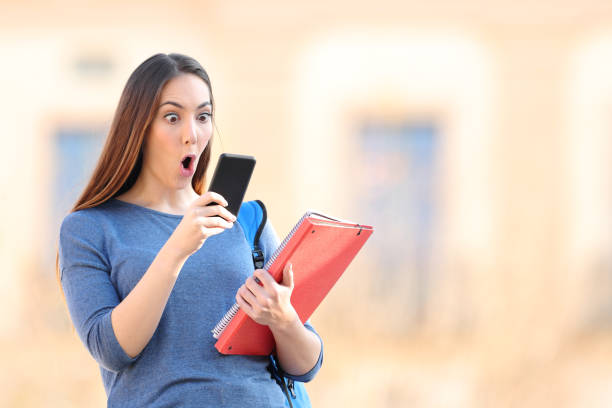 Amazed student checking mobile phone in a campus Amazed student checking mobile phone standing in an university campus i see you meme stock pictures, royalty-free photos & images