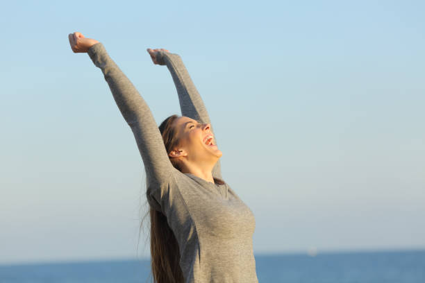 istock Excited woman celebrating success on the beach 1217030115
