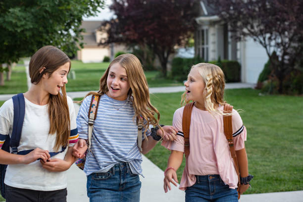 grupo de jovens amigas e estudantes conversando juntos enquanto caminham para a escola em casa para o dia - só meninas adolescentes - fotografias e filmes do acervo