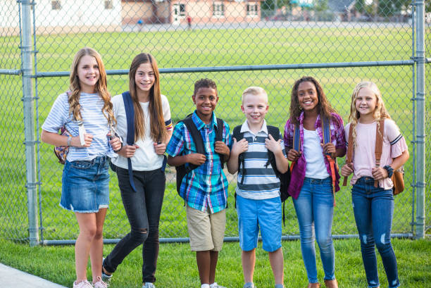 istock Group of school kids smiling while standing in a elementary school playground 1217030338