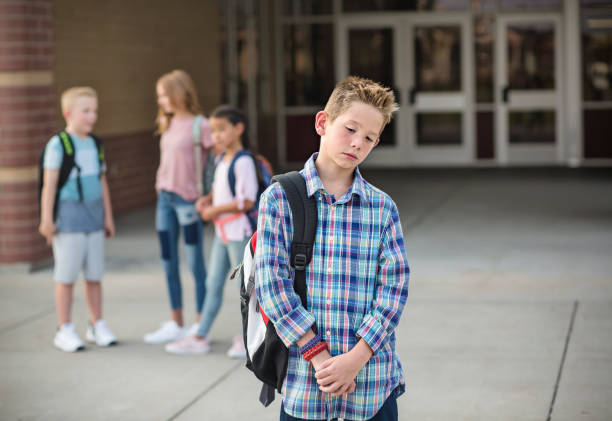 sad boy feeling left out, teased and bullied by his classmates - emotional stress looking group of people clothing imagens e fotografias de stock