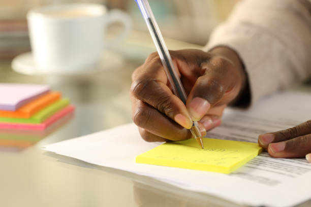 istock Black man hand writing on sticky note on a desk 1217030761