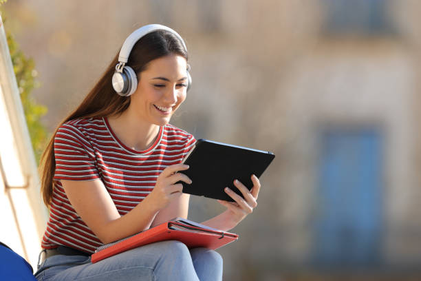 istock Happy student e learning with headphones and tablet in a campus 1217031557