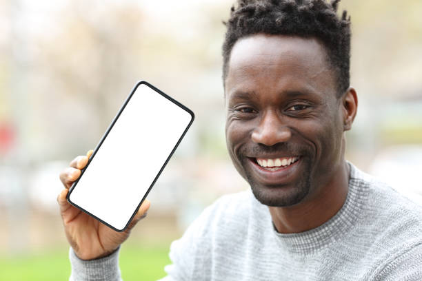 istock Happy black man showing phone with blank screen 1217031571