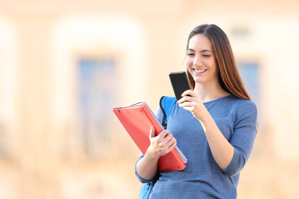 istock Happy student checking mobile phone standing in a campus 1217031582