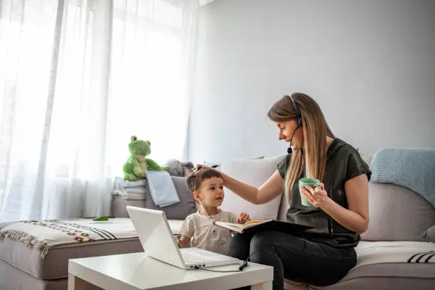 Photo of Mother working from home with kid.