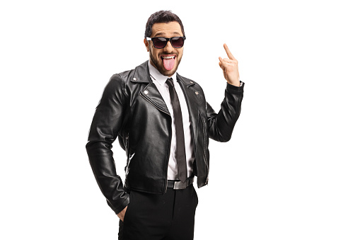 Guy wearing a leather jacket and sunglasses and gesturing a rock and roll sign isolated on white background