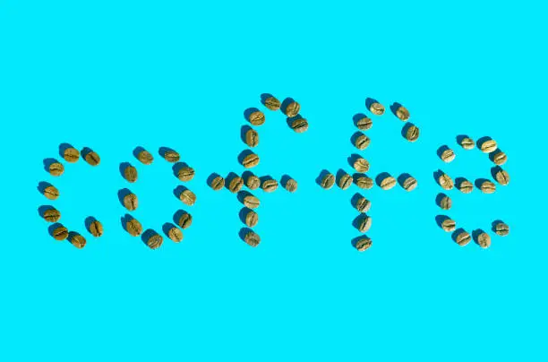 The word coffee written in grains on a blue background. Top view