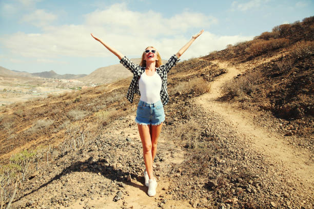 счастливая молодая женщина поднимает руки вверх по пешеходной тропе на вершине горы, тенерифе, канарские острова, испания - b4 стоковые фото и изображения