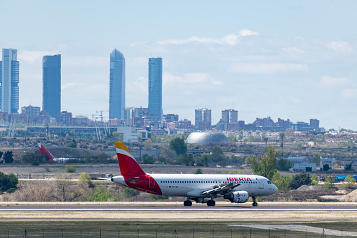 MADRID, SPAIN - APRIL 14, 2019: Iberia Airlines Airbus A320 passenger plane landing at Madrid-Barajas International Airport Adolfo Suarez In the background we can see the city of Madrid, with the towers of the financial district.