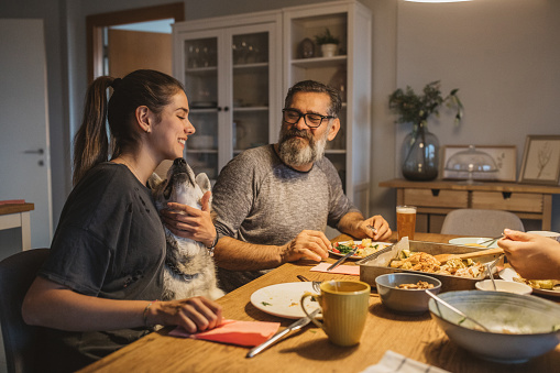 Family have diner during isolation period. Pet dog wants some treats from table