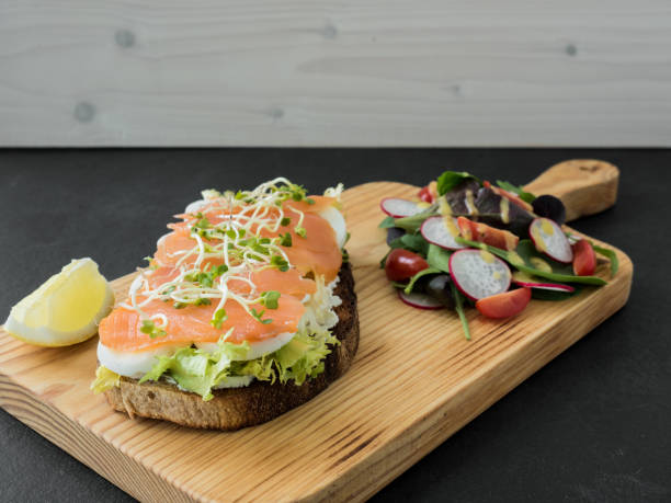 istock Smoked salmon bruschetta and salad on a wonden board. 1217041679