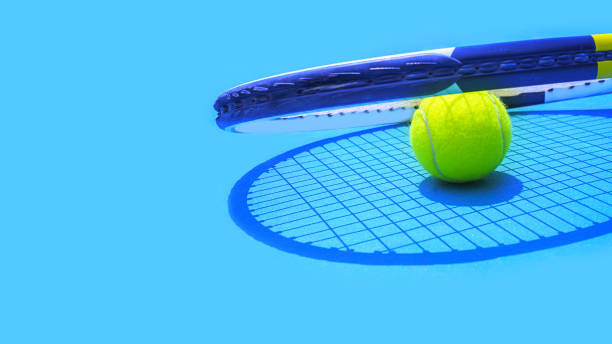 Summer sport concept with tennis ball and racket on blue hard tennis court. Summer sport concept with tennis ball and racket on blue hard tennis court. Top view, copy space. courtyard photos stock pictures, royalty-free photos & images
