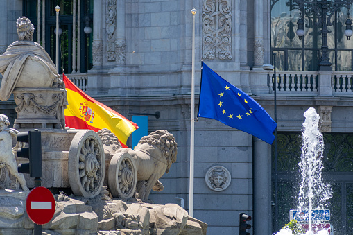 MADRID, SPAIN - MAY 11, 2019: The flags of Spain and the European Union fly in front of the Bank of Spain's headquarters in the famous Plaza de Cibeles.