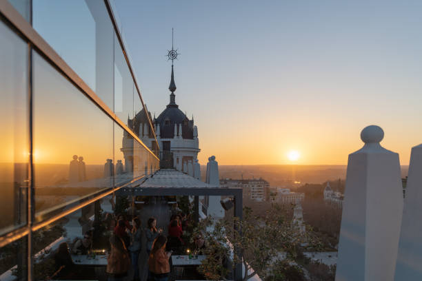 Clients relaxing and having an aperitif on one of the many hotel rooftop terraces during the sunset in Madrid. stock photo