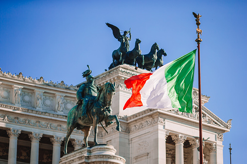 Italian flag on background on famous Vittoriano with gigantic equestrian statue of King Vittorio Emanuele II in Rome