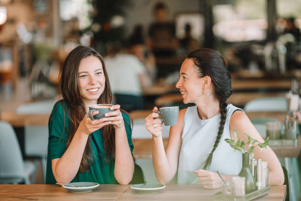 istock Happy smiling young women with coffee cups at cafe. 1217049555