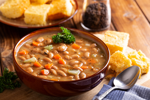Bowl of tasty bean soup with cornbread on a wooden table