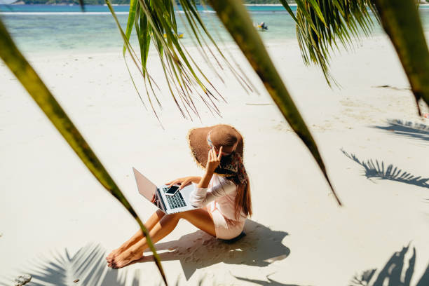 istock woman with laptop on beach in tropics 1217053907
