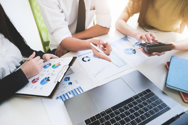 A male business consultant describes a marketing plan to set business strategies for women business owners with using calculator. business planning and business researching concept. un consultor de negocios masculino describe un plan de marketing para establecer estrategias de negocio para las mujeres propietarias de negocios con el uso de calculadora. concepto de planificación empresarial e investigación empresarial.