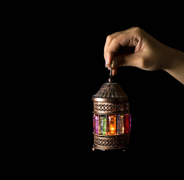 istock Female hand holding Ramadan lantern on a black background 1217059890