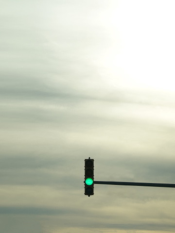 A single red traffic light up against an overcast sky with plenty of Copy Space.