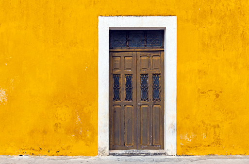 Yellow wall facade and door in the city center of Izamal, Yucatan Peninsula, Mexico.