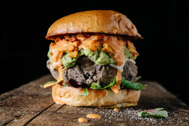 A close-up of a vegetarian burger with avocado and cheese