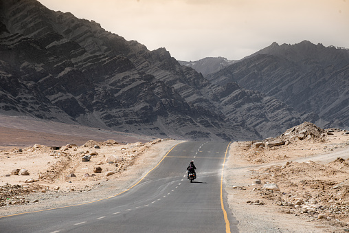 Biker ride through a desert alone with vintage motorbike