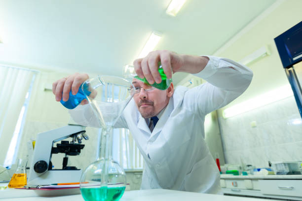 istock Chemist crazy. A mad scientist conducts experiments in a scientific laboratory. With a mad expression on his face, he mixes two liquids in a flask. COVID-19. COVID Coronavirus 1217074199