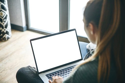 Girl at home uses laptop mockup. Modern technology in everyday life. Blank white screen place for text or template.